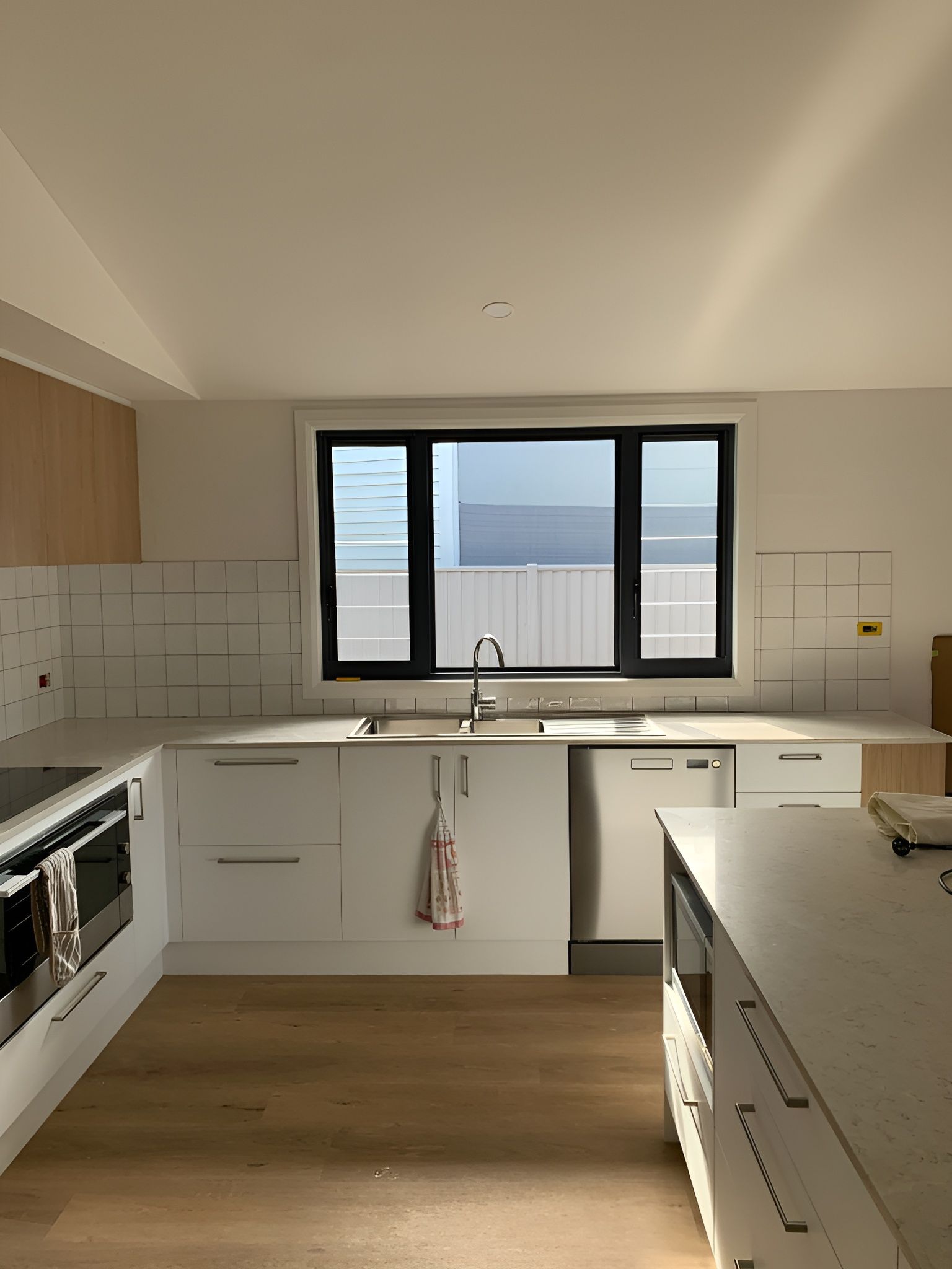 Modern Kitchen with White Cabinets, Wood Floor — Midcoast Wall & Floor Tiling in Boambee East, NSW