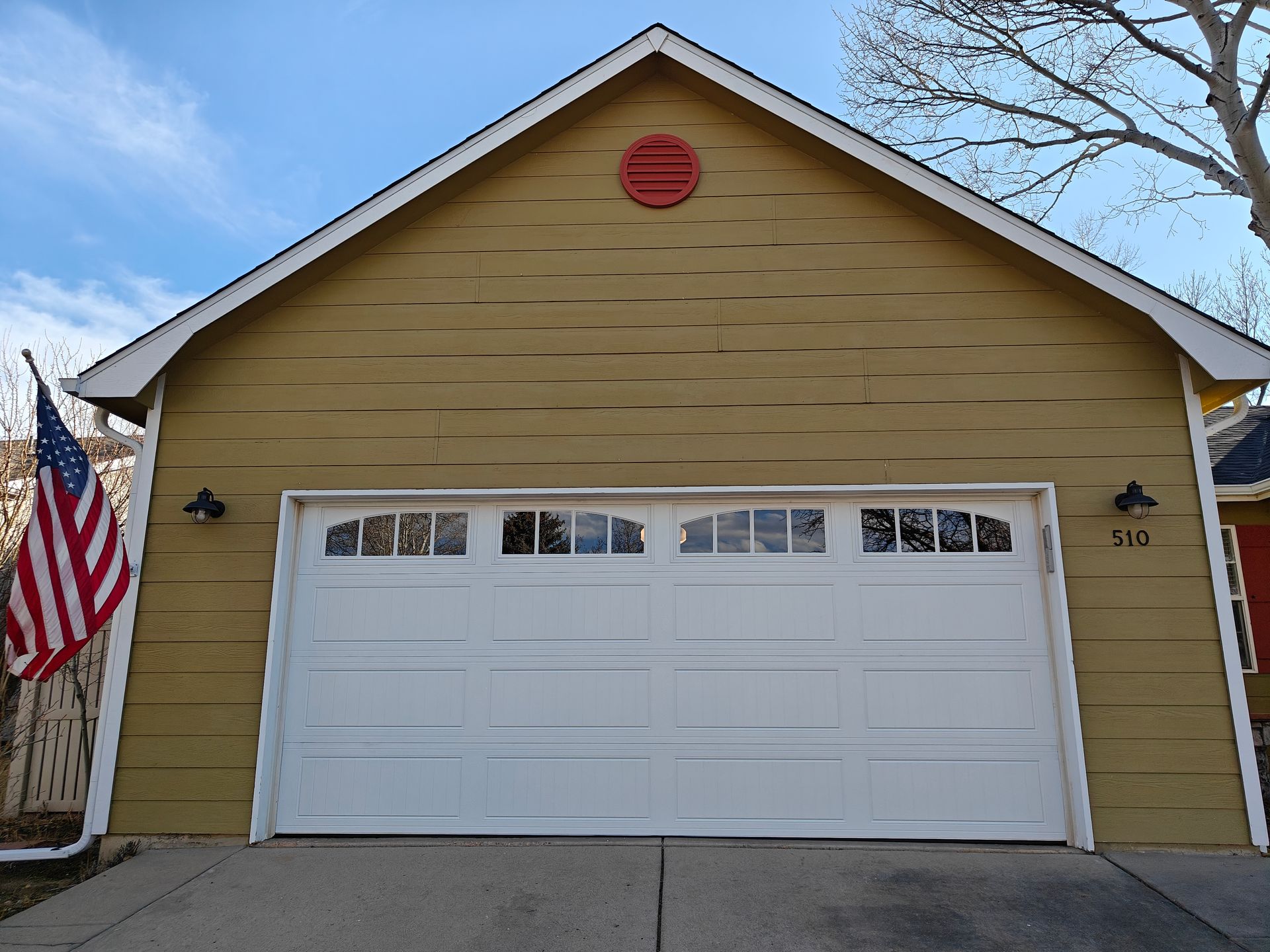 Yellow garage with a white door and an American flag on the left side.