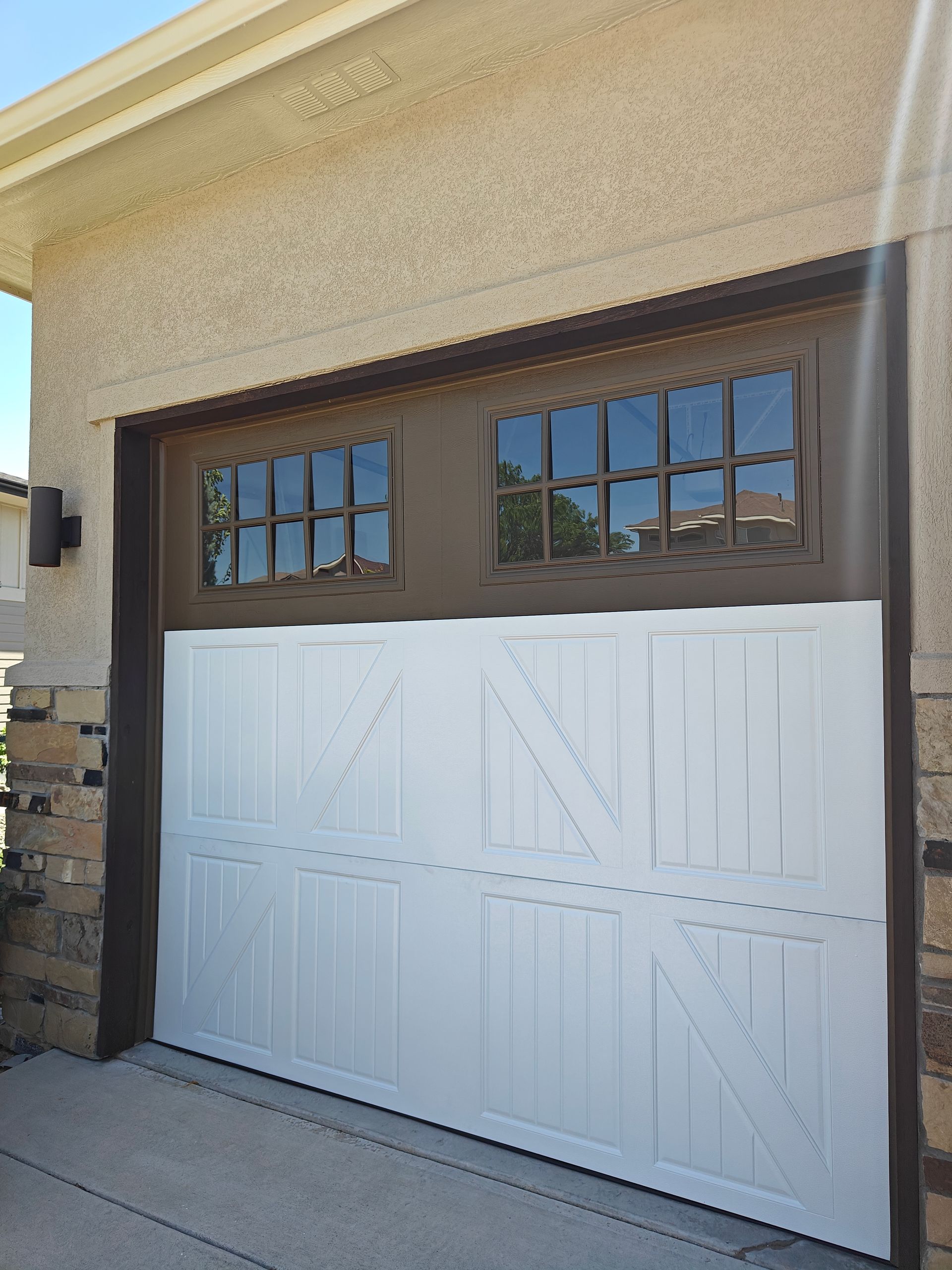 Open garage with raised door, black car parked inside, and a person loading the trunk.
