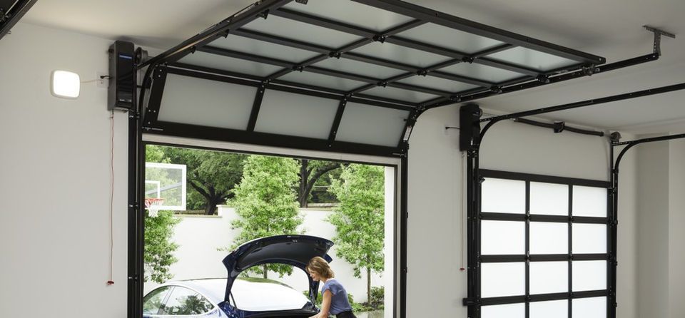 Open garage with raised door; person loads items into a car trunk near a driveway.