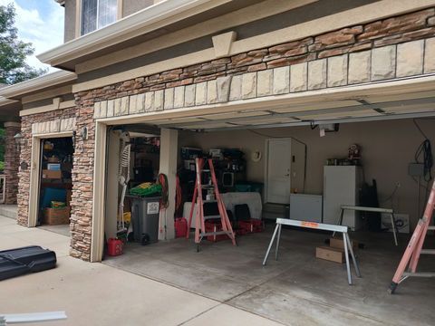 Open garage under construction with tools, ladders, and work tables in front of a house