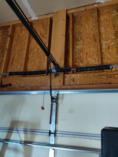 Garage ceiling with wooden rafters and metal garage door opener rails.