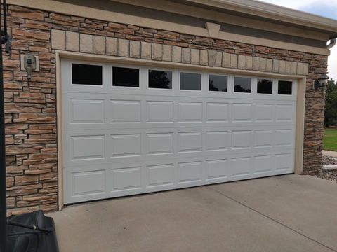 White garage door on a stone-front house with concrete driveway.