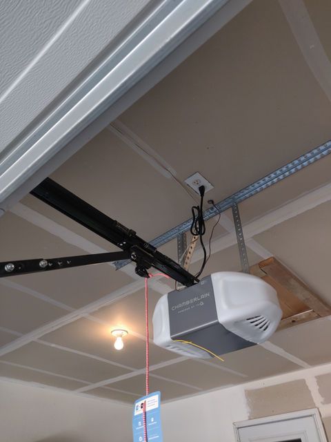 Garage ceiling with a mounted garage door opener and rail, plus a hanging light bulb.