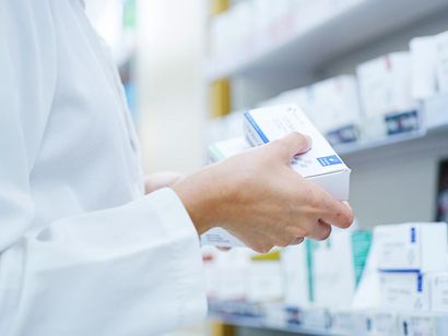 Un farmacista tiene in mano una scatola di pillole in una farmacia.