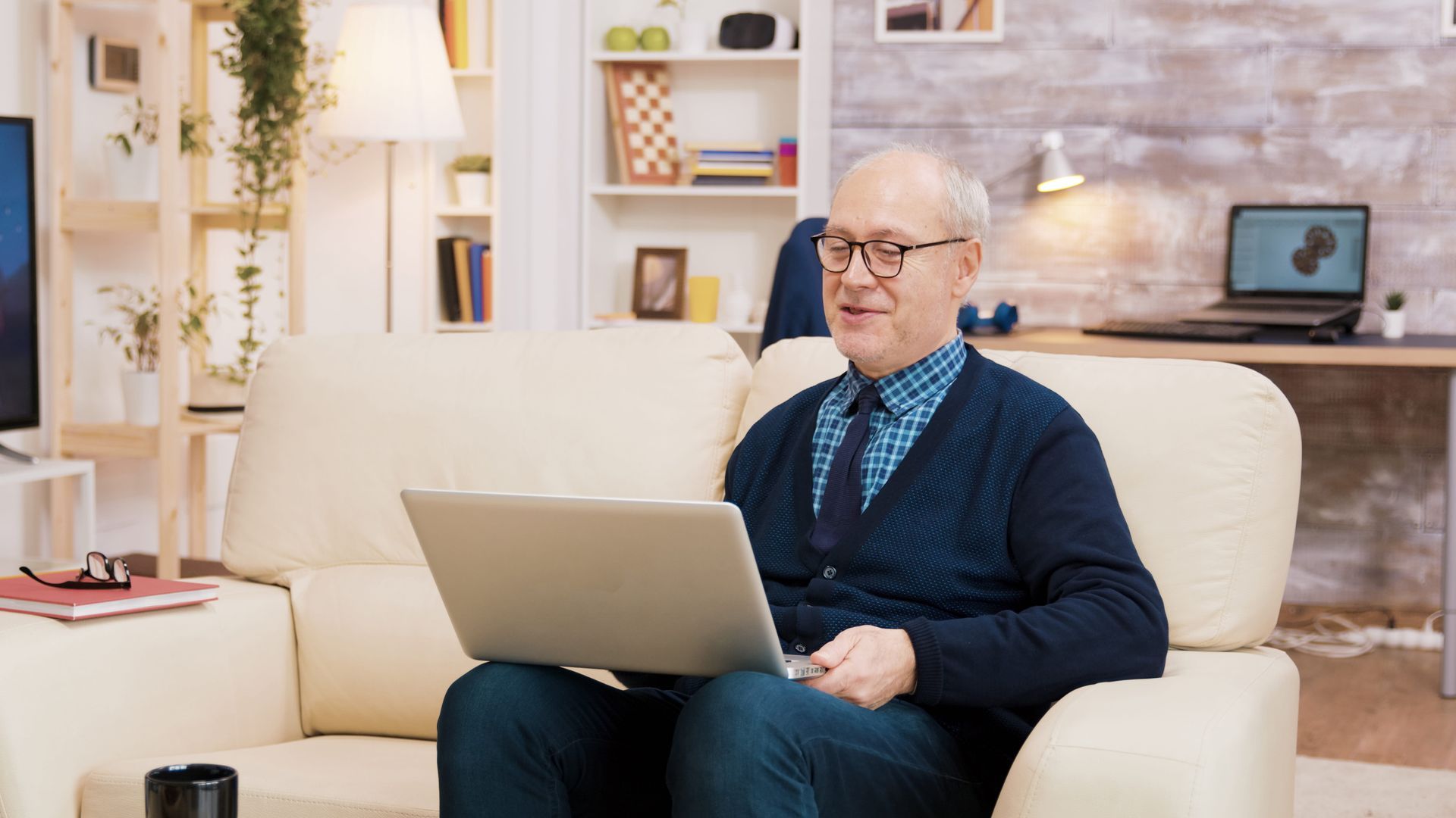 Person smiling and typing on a laptop at a table in a bright room