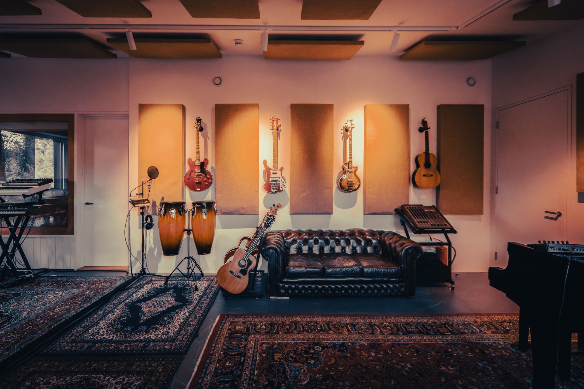 a room with a couch , guitars , drums and a piano .