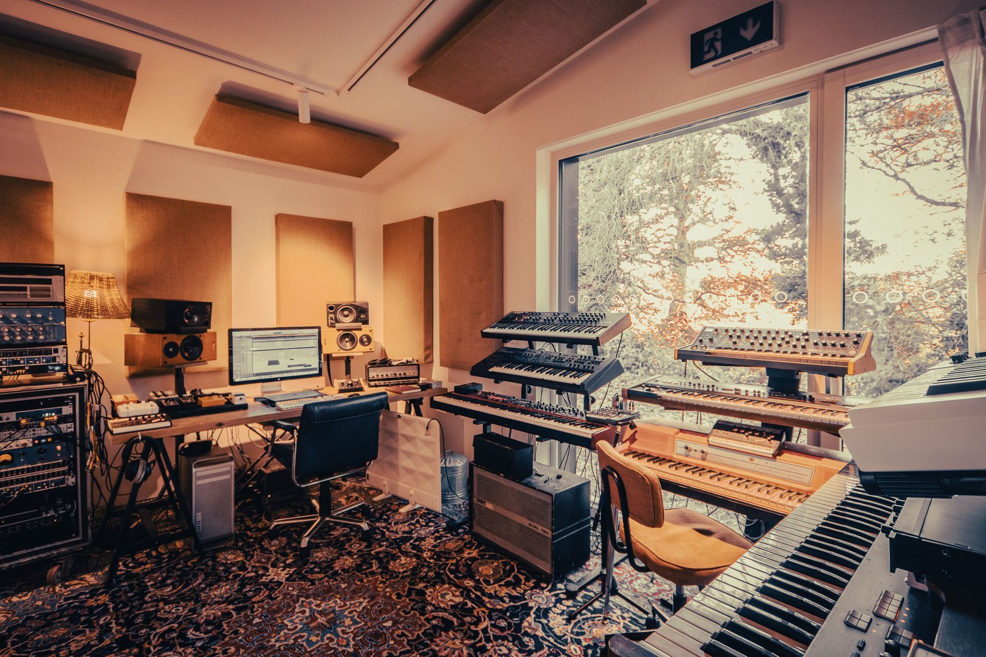 a recording studio with a lot of instruments and a large window .
