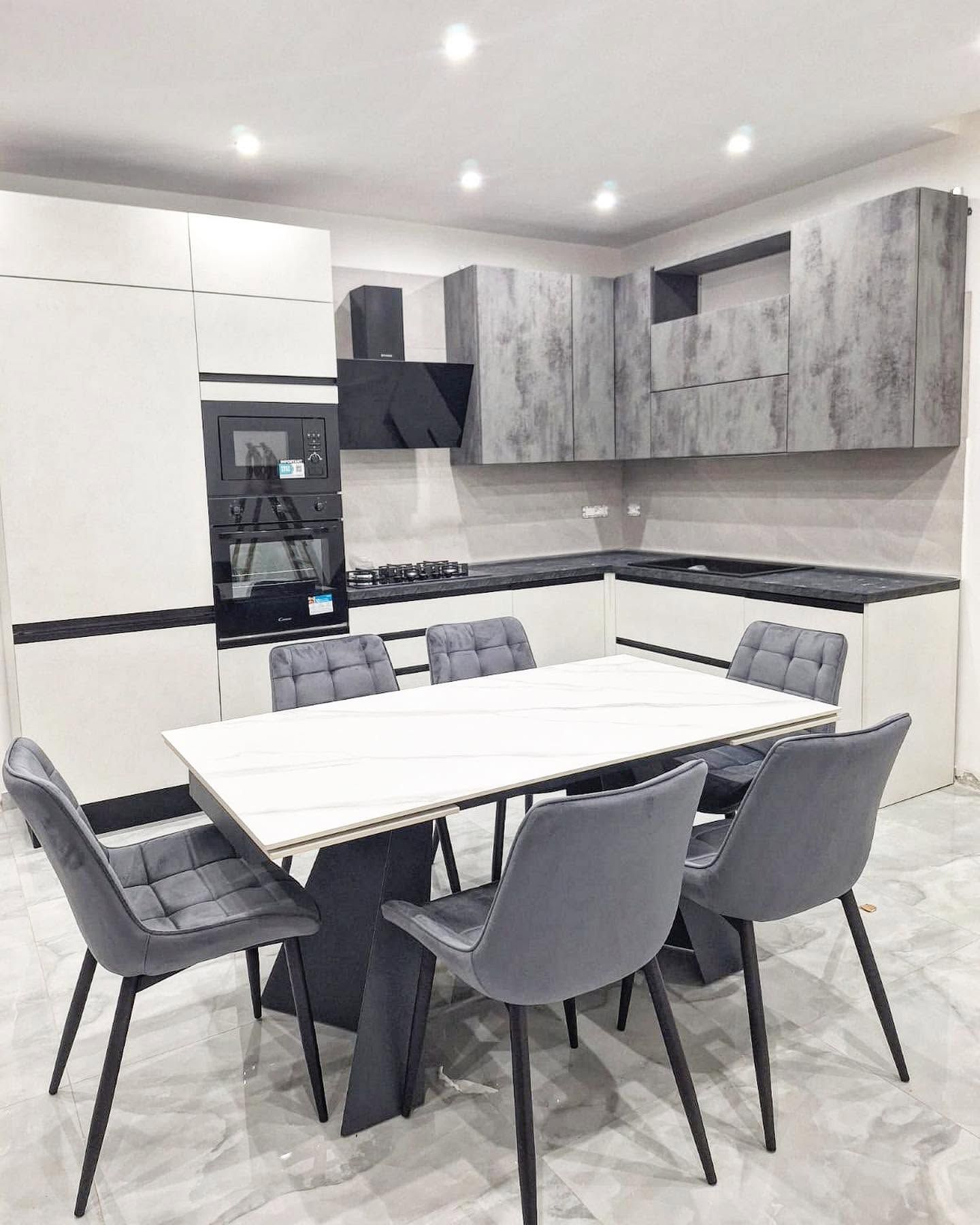 Cucina moderna con mobili effetto marmo e un tavolo da pranzo bianco circondato da sedie grigie
