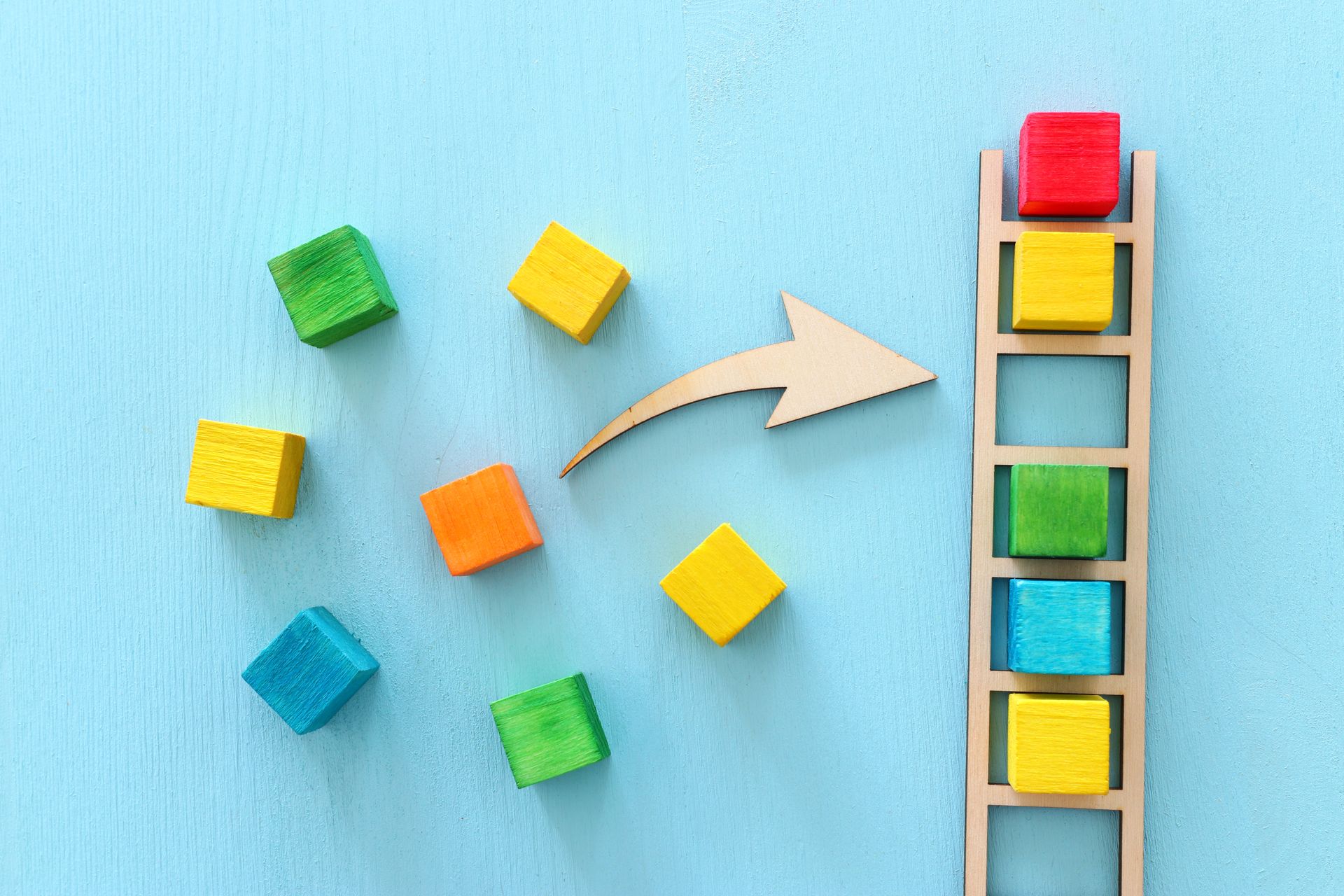 A wooden ladder with colorful wooden blocks and an arrow pointing up.