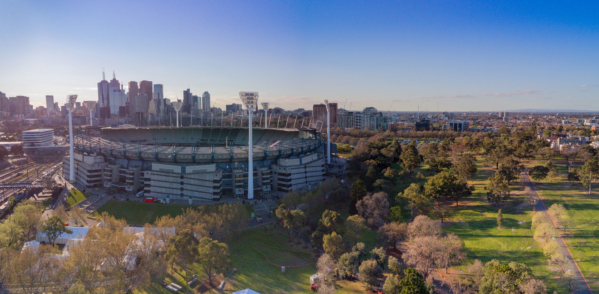 An aerial view of a stadium surrounded by trees and a city skyline.