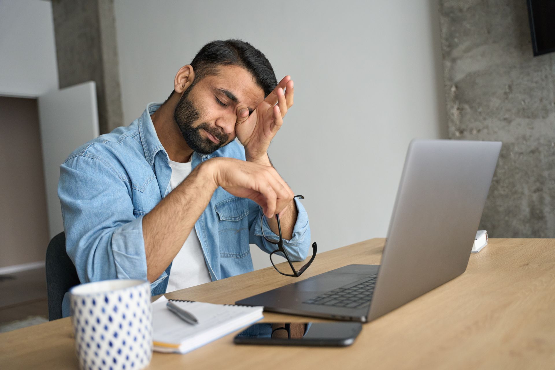 A man is sitting at a desk in front of a laptop computer.