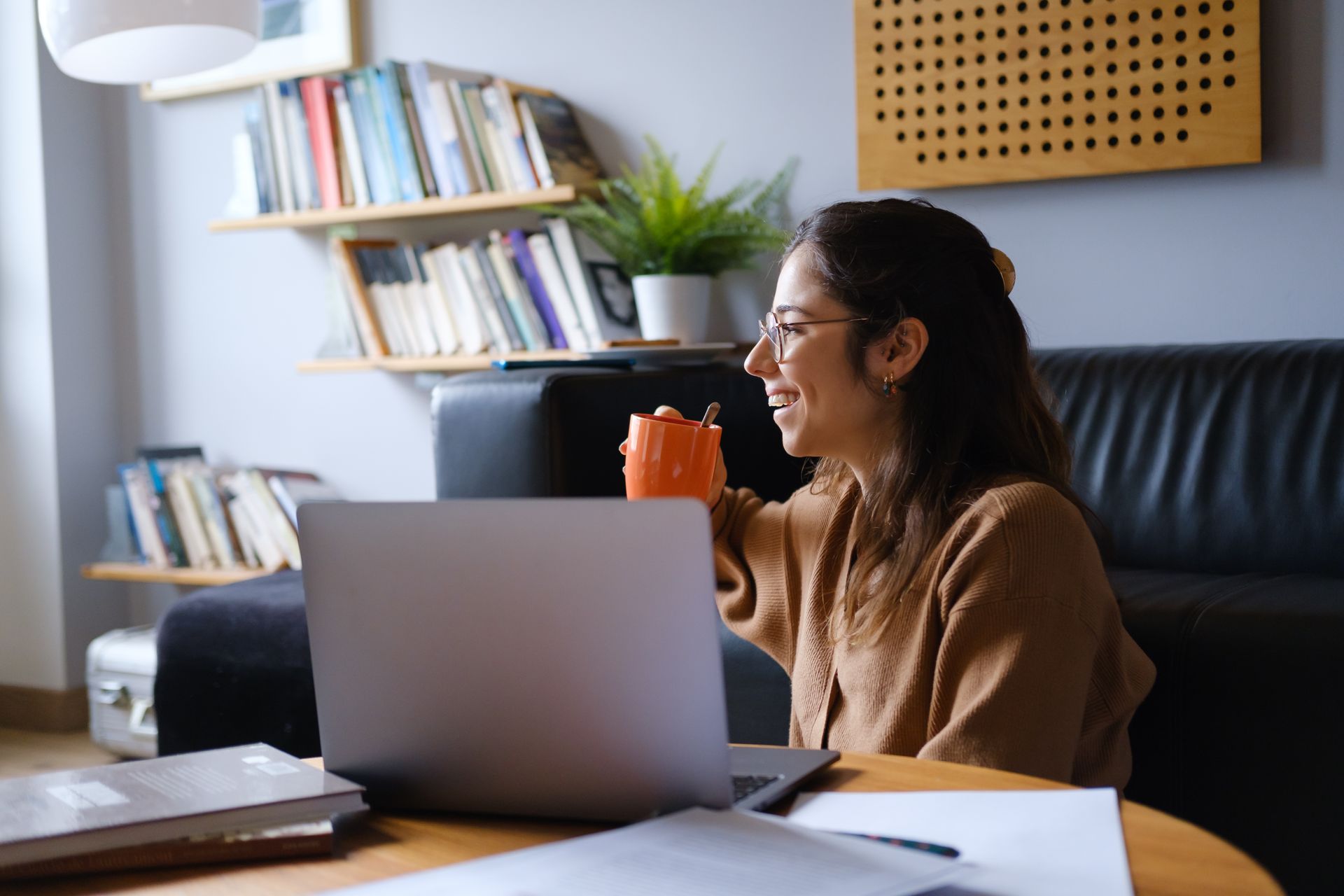 A woman is sitting at a table with a laptop and a cup of coffee.