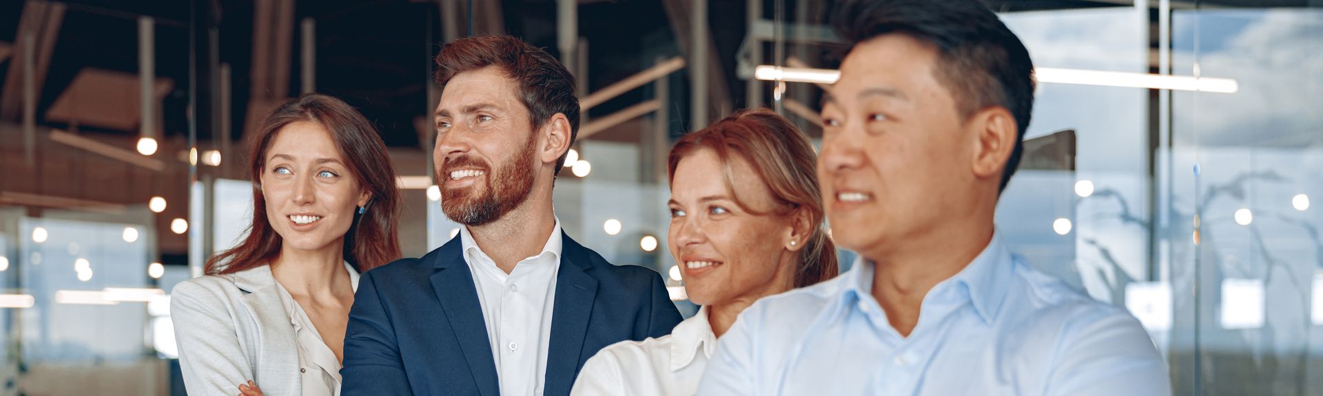 A group of business people are standing next to each other in an office and smiling.