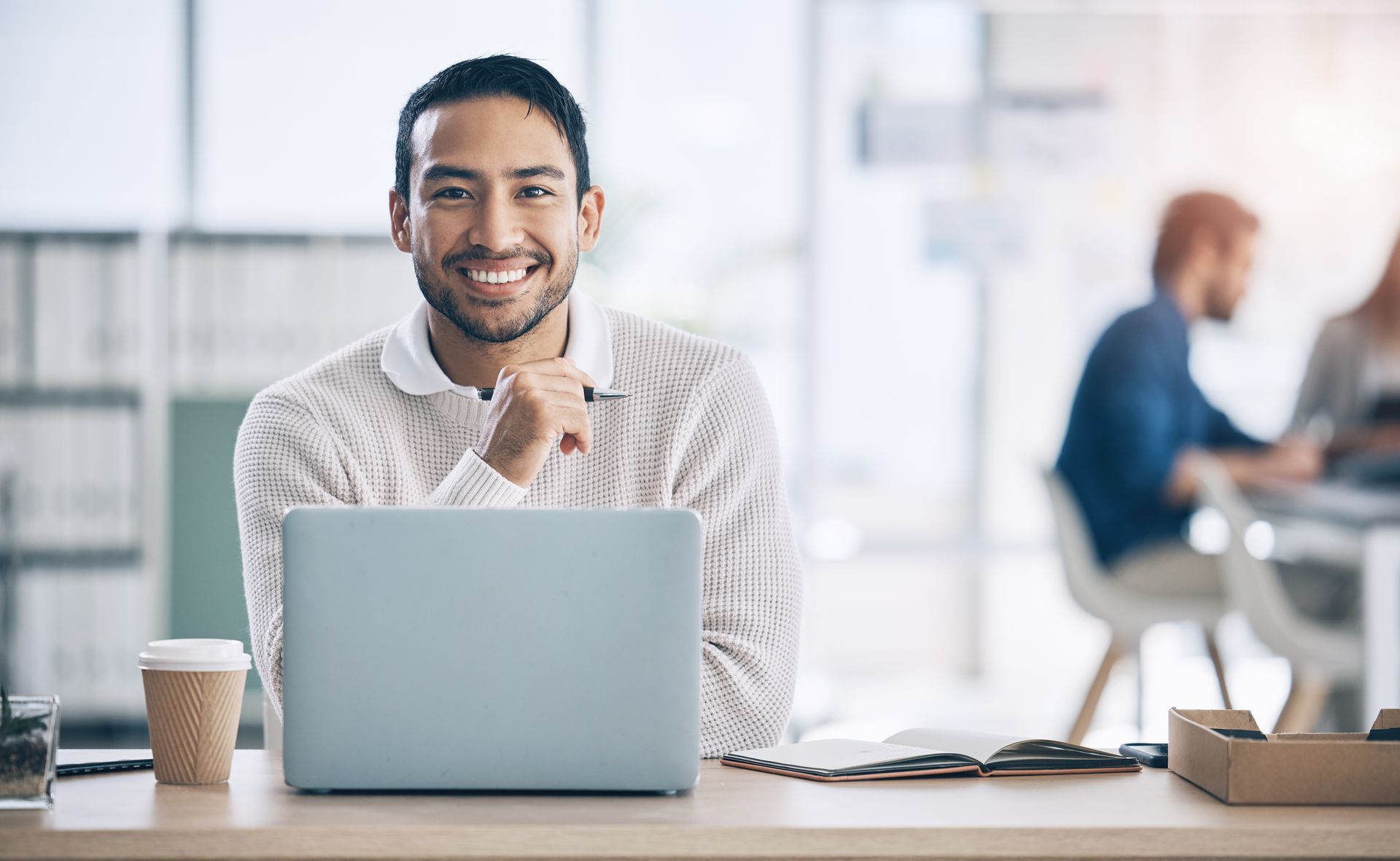 A man is sitting at a desk in front of a laptop computer.