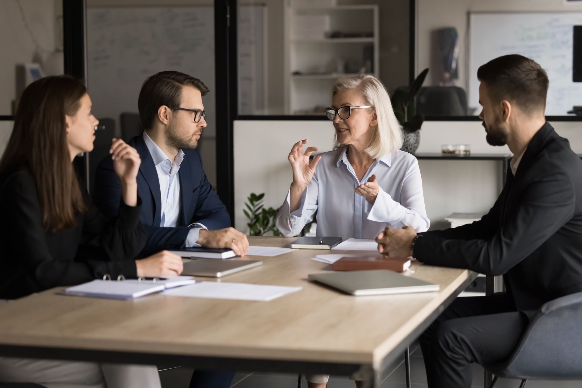 A group of people are sitting around a table having a meeting.
