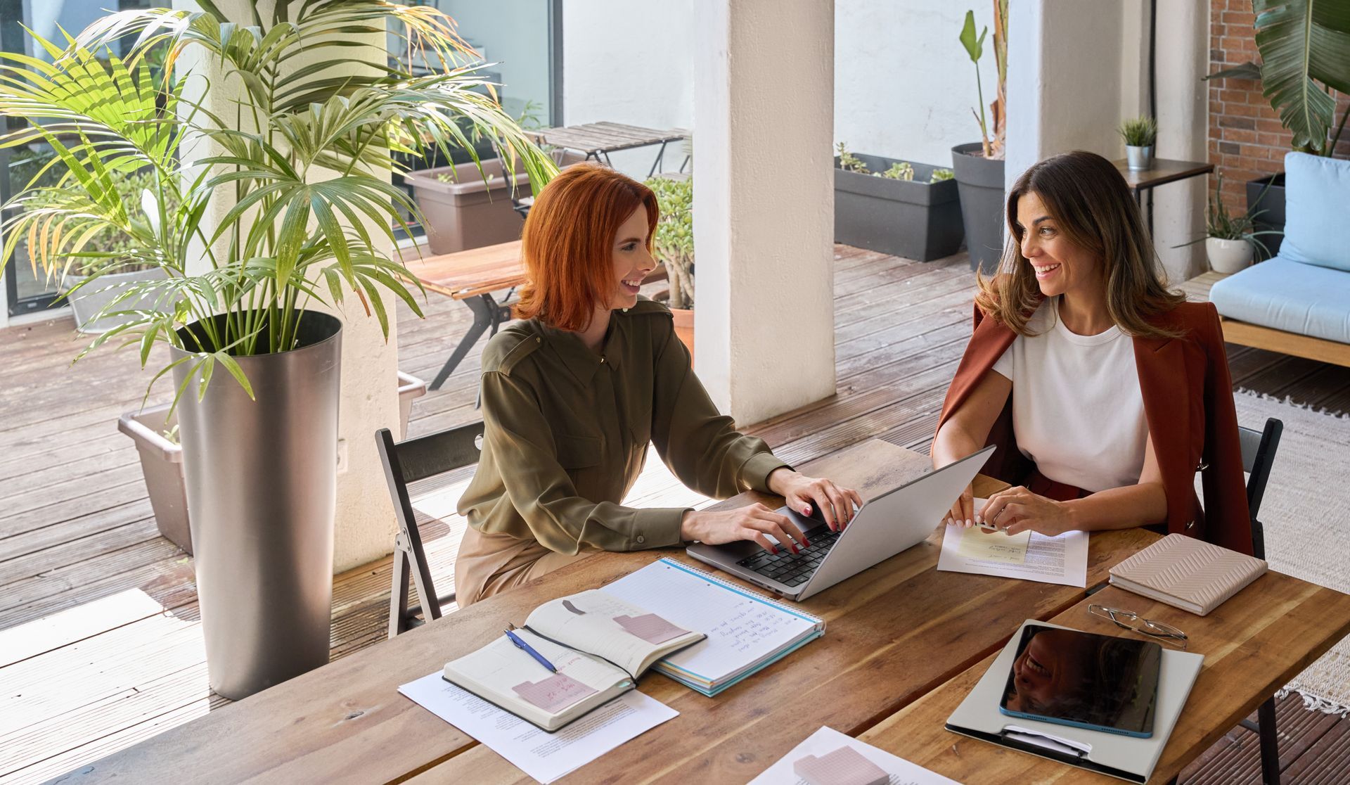 Two women are sitting at a table with a laptop.
