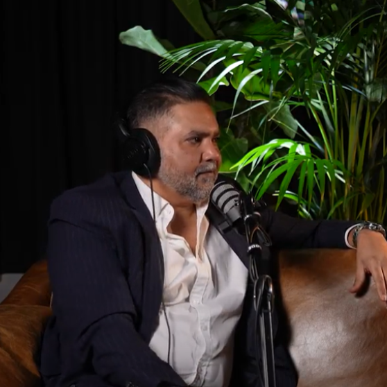 A man wearing headphones is sitting in front of a microphone