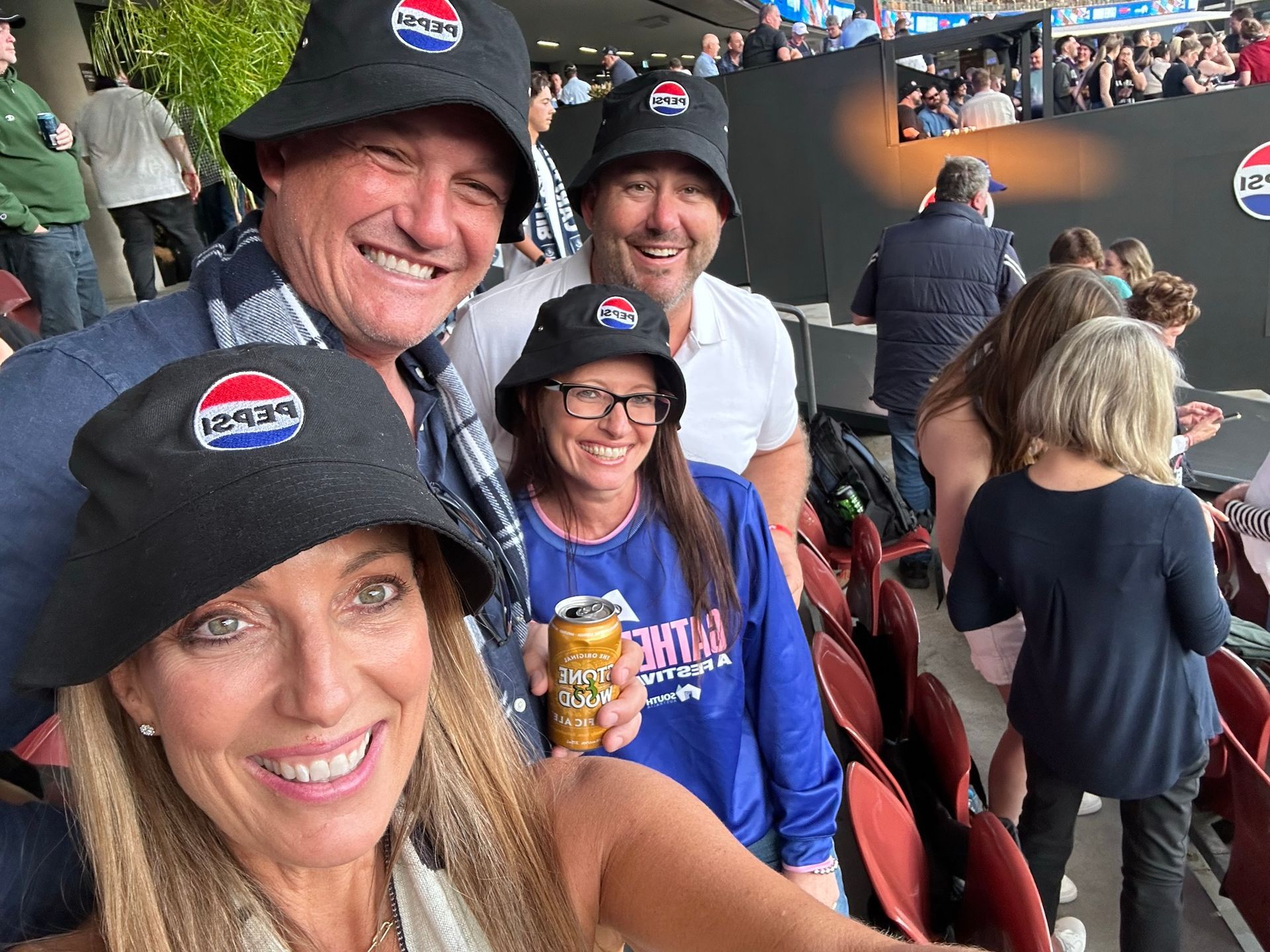 A group of people wearing pepsi hats are sitting in a stadium.