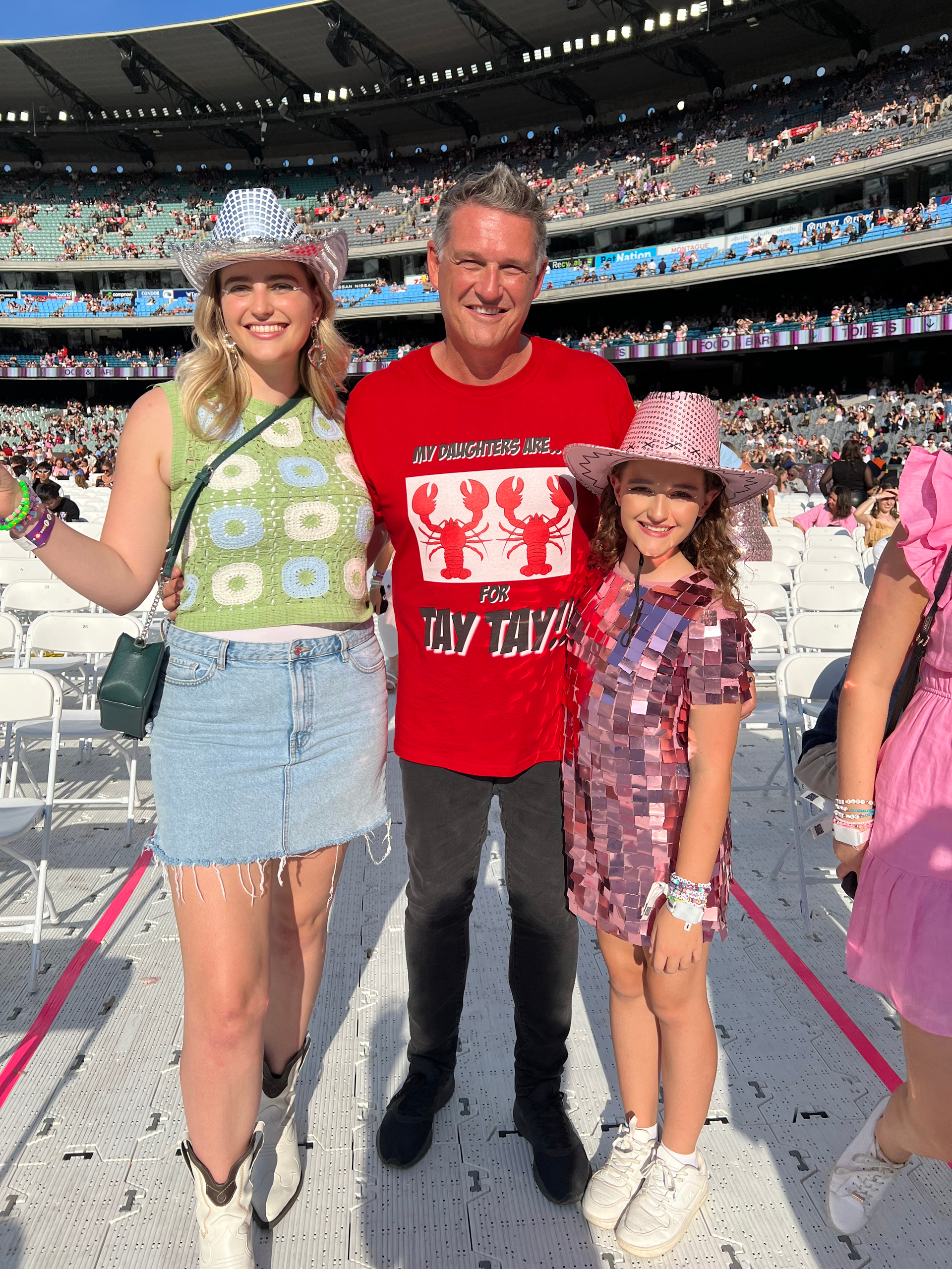 A man and two girls are standing next to each other in a stadium.