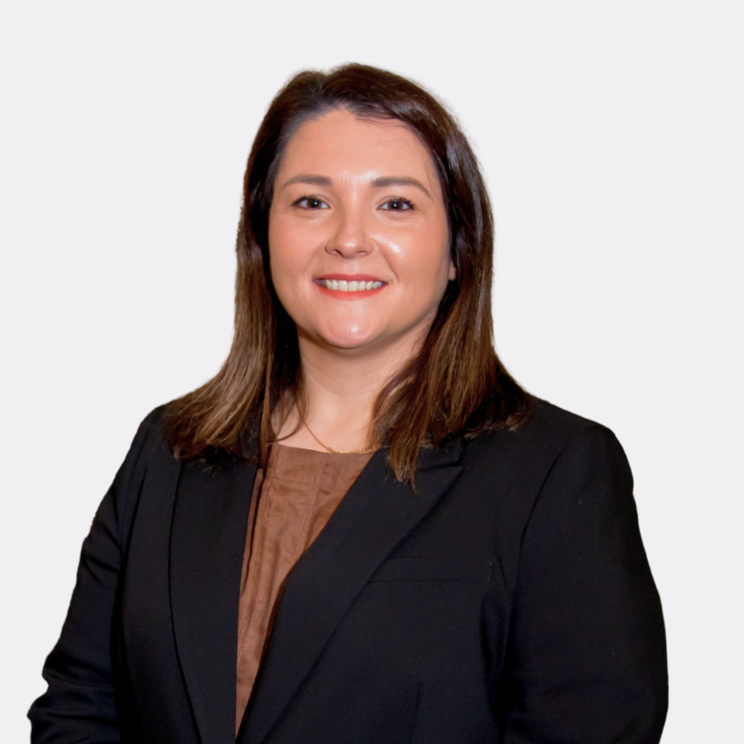 A woman in a black jacket is smiling with her arms crossed.