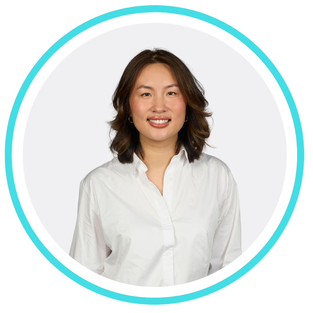 A woman in a black jacket is smiling with her arms crossed.