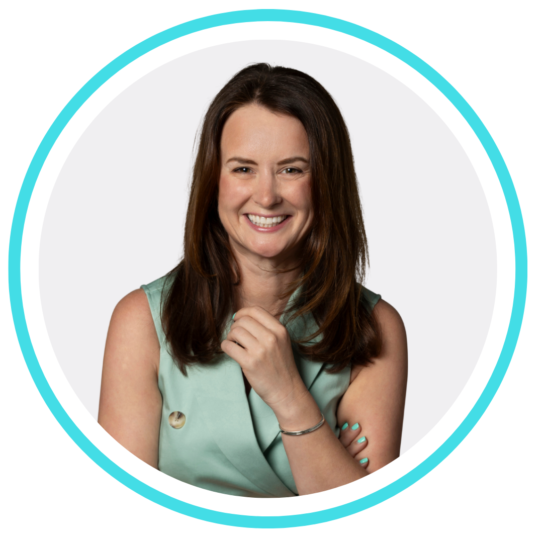 A woman in a black jacket is smiling with her arms crossed.