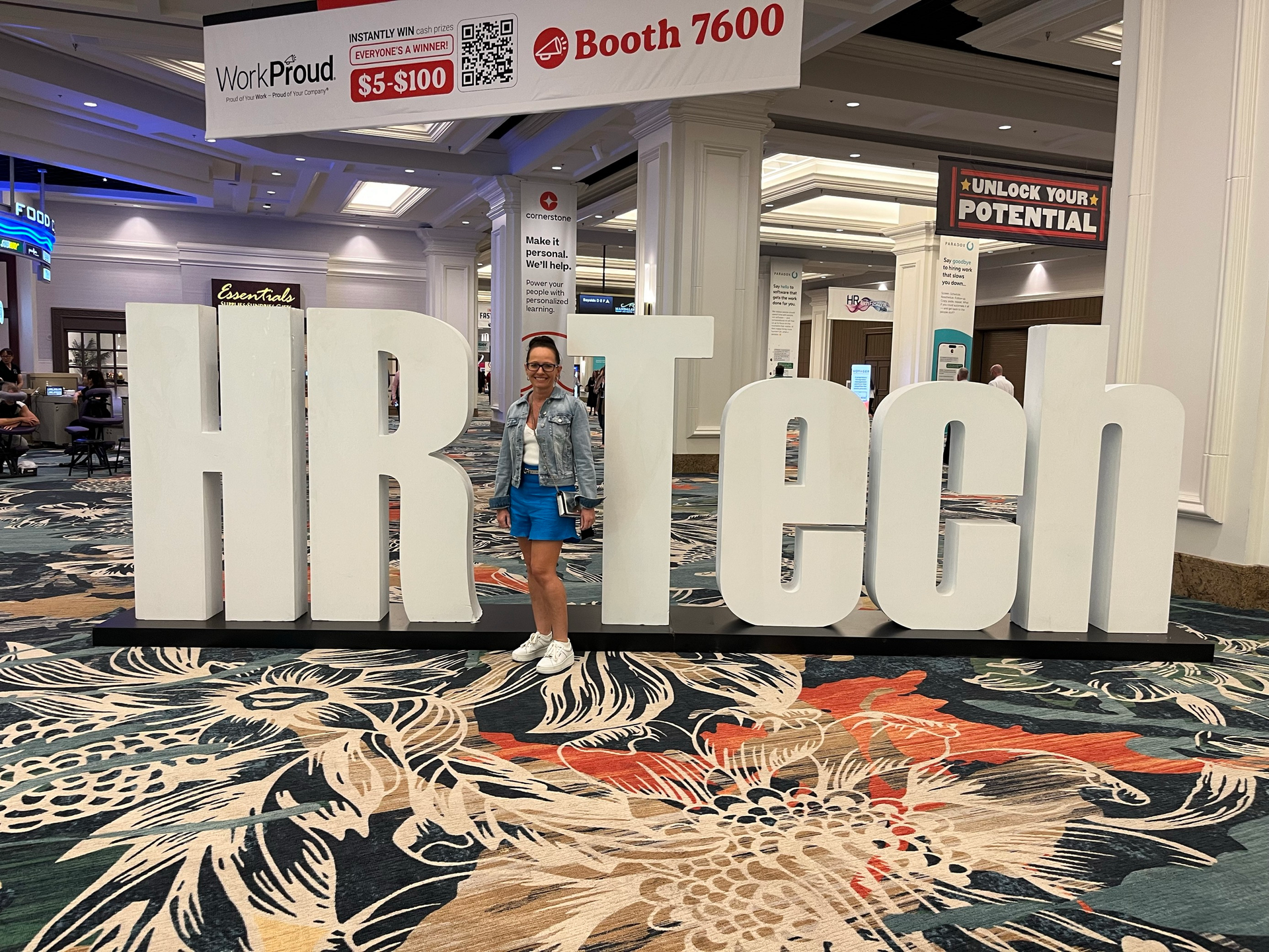 A woman is standing in front of a large sign that says hr tech.