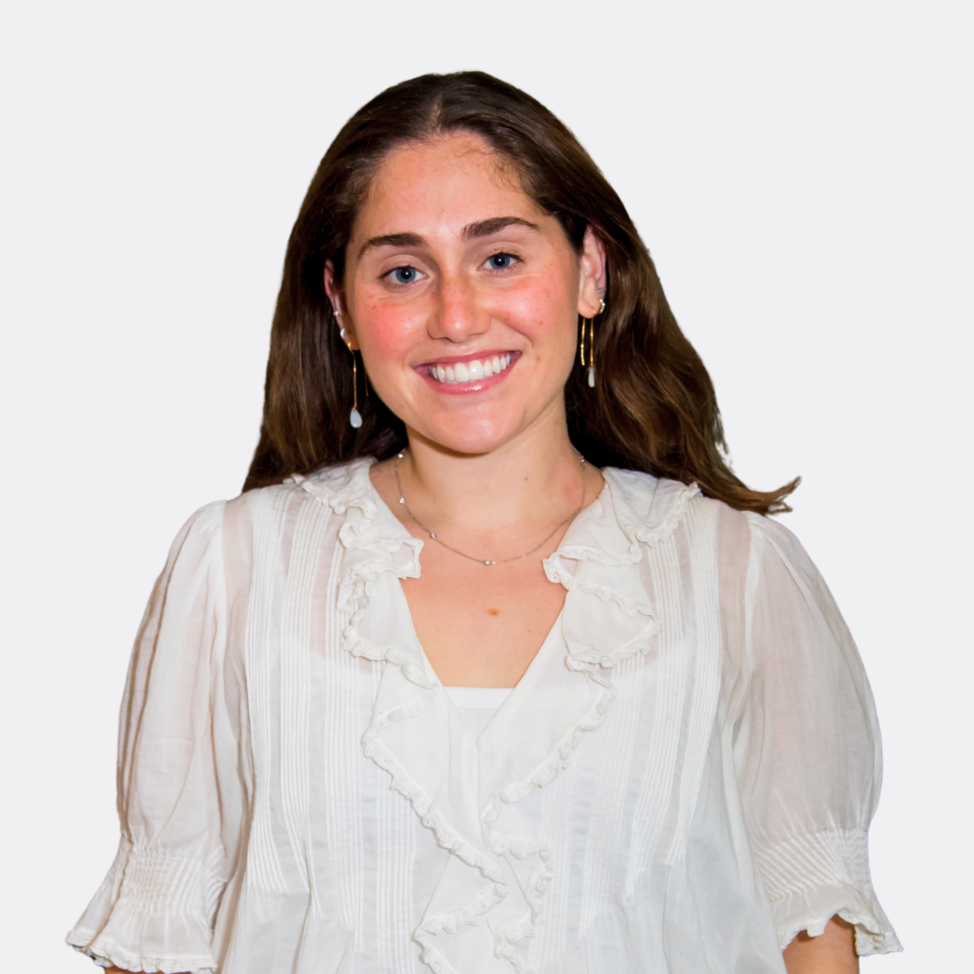 A woman wearing a white shirt and a pink belt is smiling for the camera.