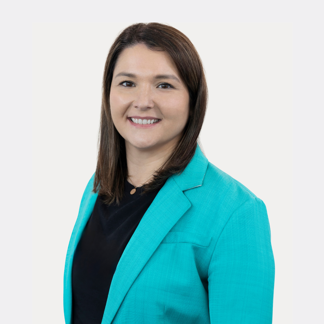 A woman in a black jacket is smiling with her arms crossed.