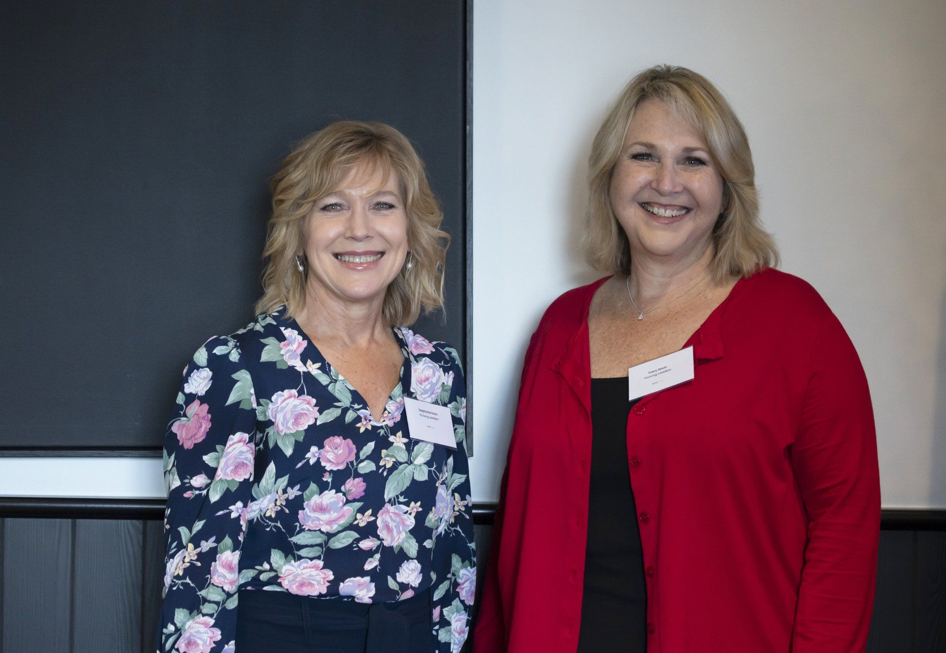 Two women are standing next to each other and smiling for the camera.