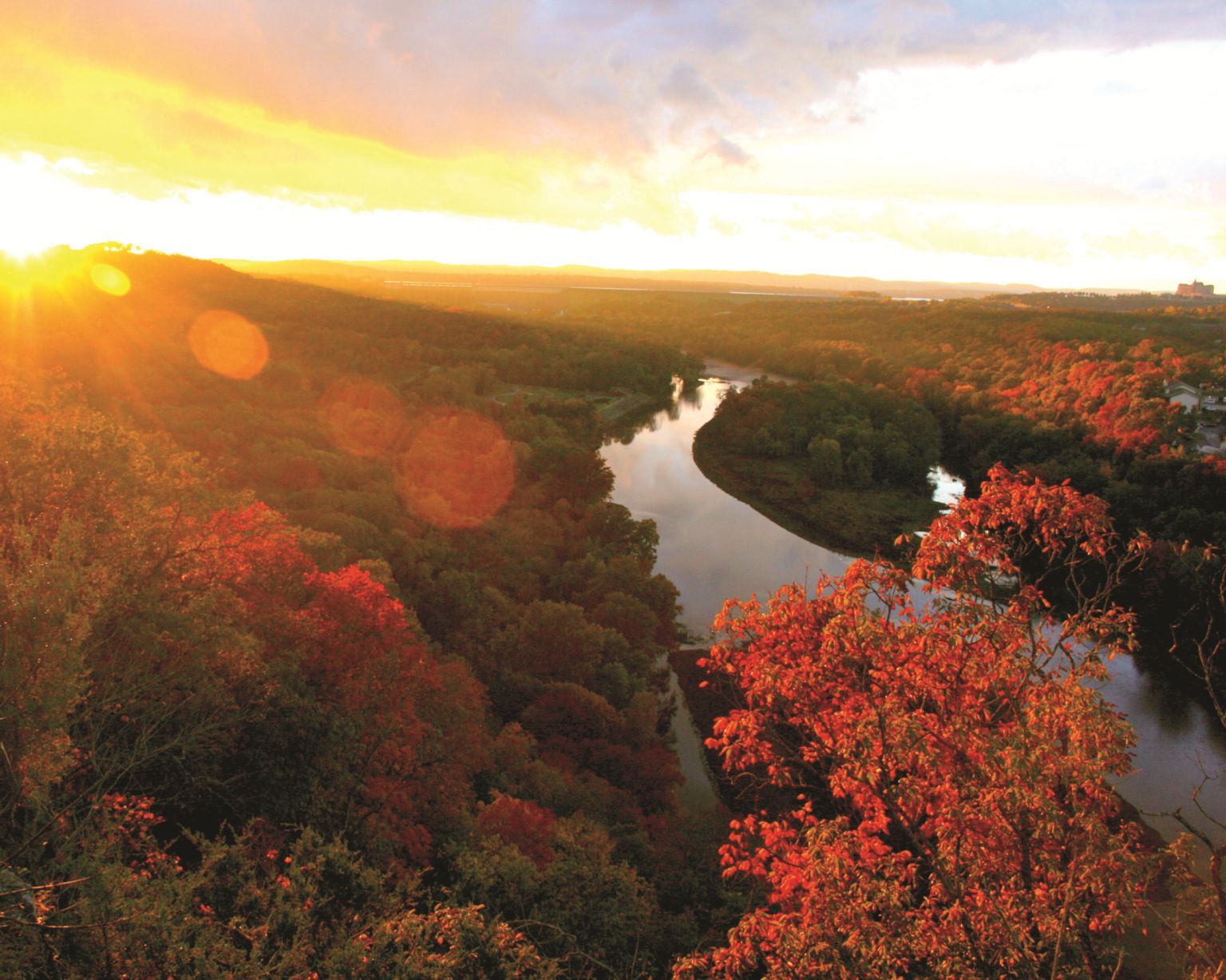Sunset over a winding river through dense autumn forest