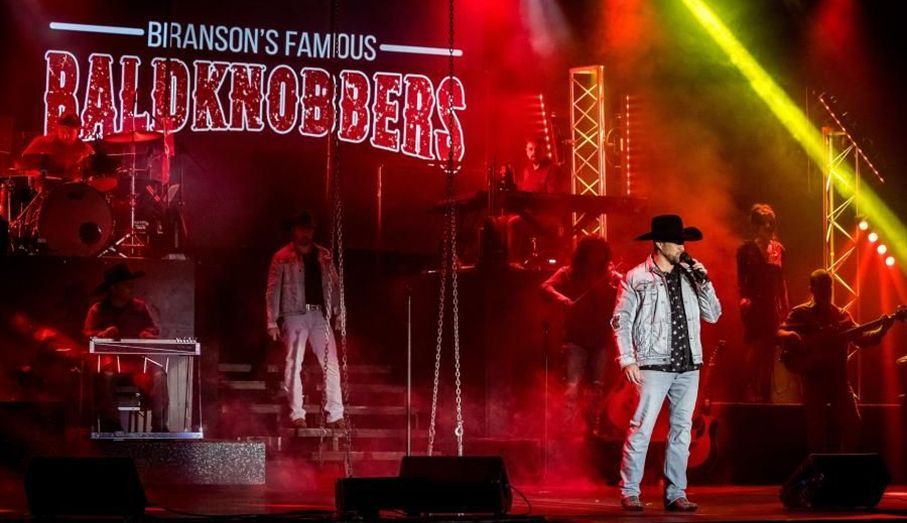 Concert stage with red lighting, performers in black and white cowboy outfits, and “Branson’s Famous Baldknobbers” sign