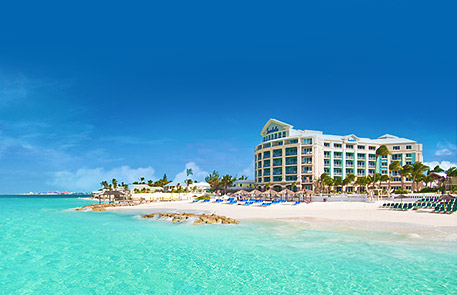 Beachfront resort with white building, turquoise water, and clear blue sky.