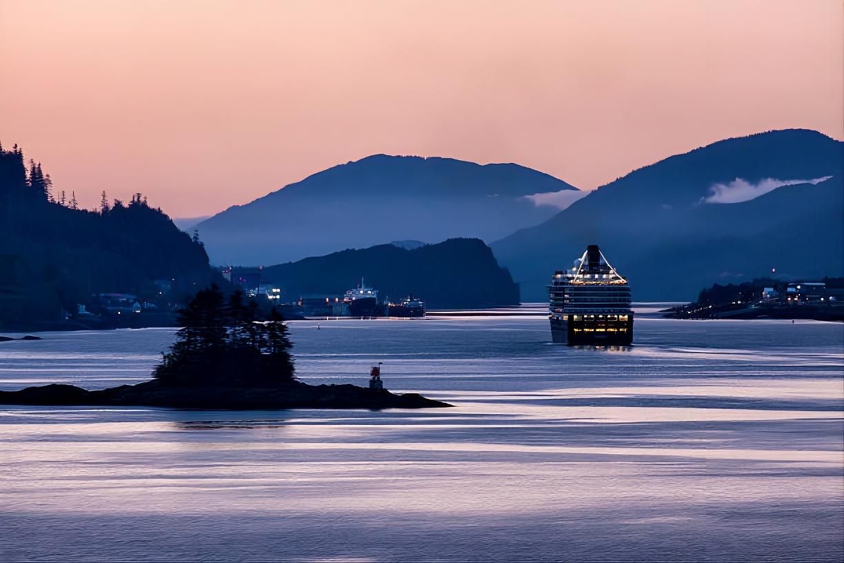 Twilight seascape with silhouetted islands, calm water, and a lit cruise ship under pink-blue sky