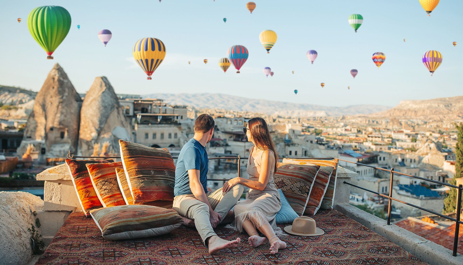 Couple on a rooftop with hot air balloons over Cappadocia, Turkey.