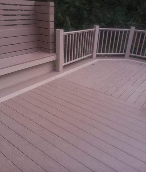 Composite deck with built-in bench and railing. Light brown with matching color trim. Outdoor setting.