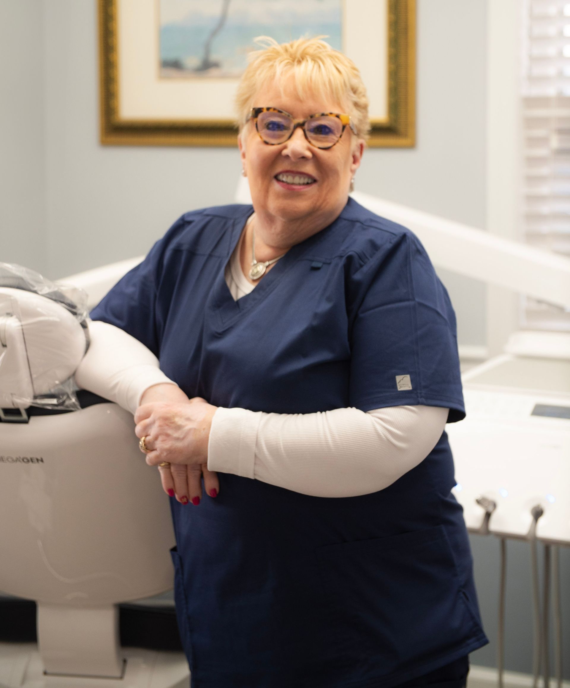 A woman wearing glasses and a red shirt is smiling for the camera.