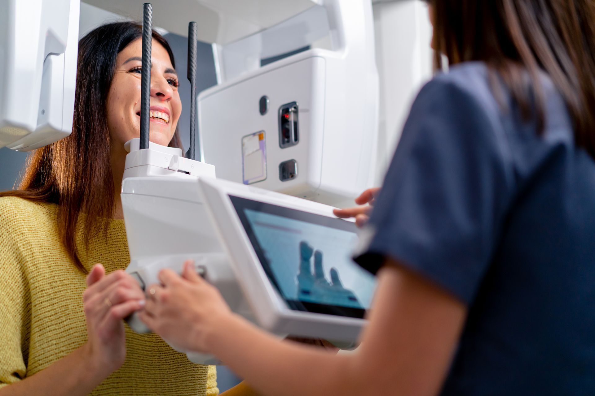 A woman is smiling while getting an x-ray of her teeth.