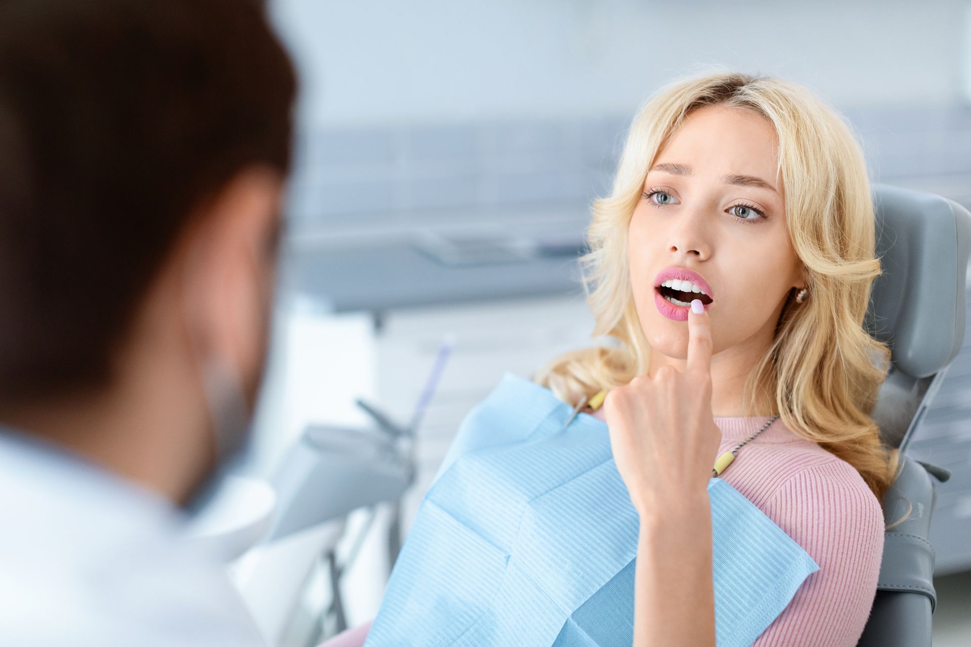 A woman is sitting in a dental chair talking to a dentist.