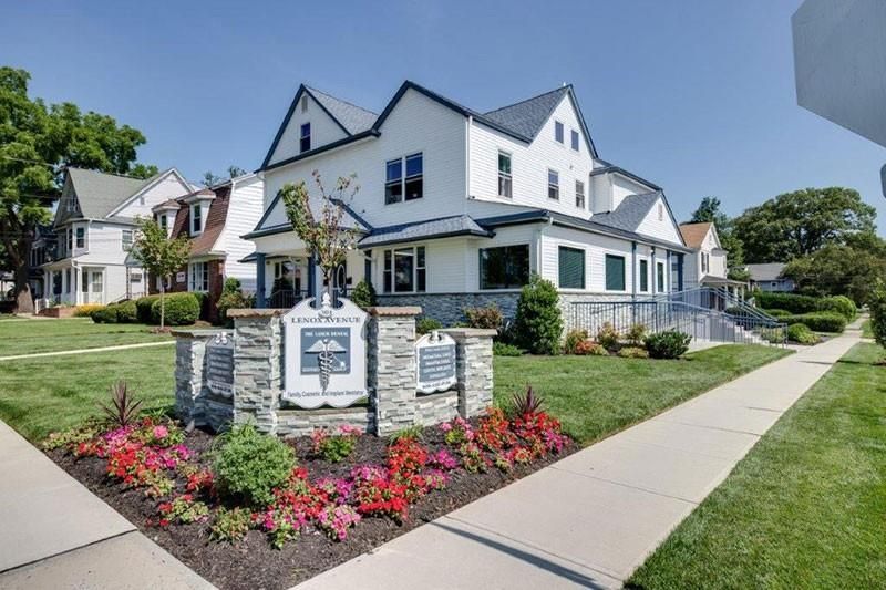 A large white house with a sign in front of it.