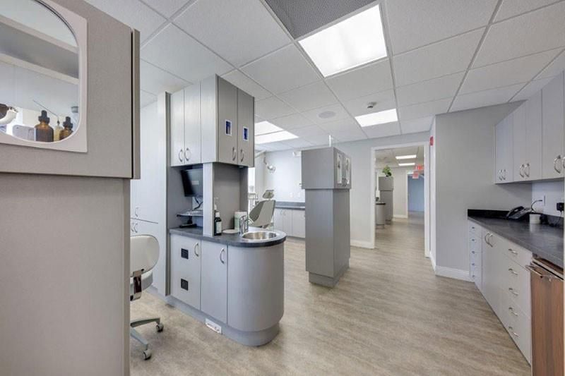 A dental office with a lot of cabinets and a dental chair.