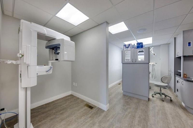 A dental office with a x-ray machine in the middle of the room.