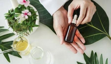 Una persona sostiene una botella de aceite esencial en la mano.