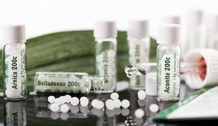 Un grupo de frascos de medicina homeopática están sobre una mesa.