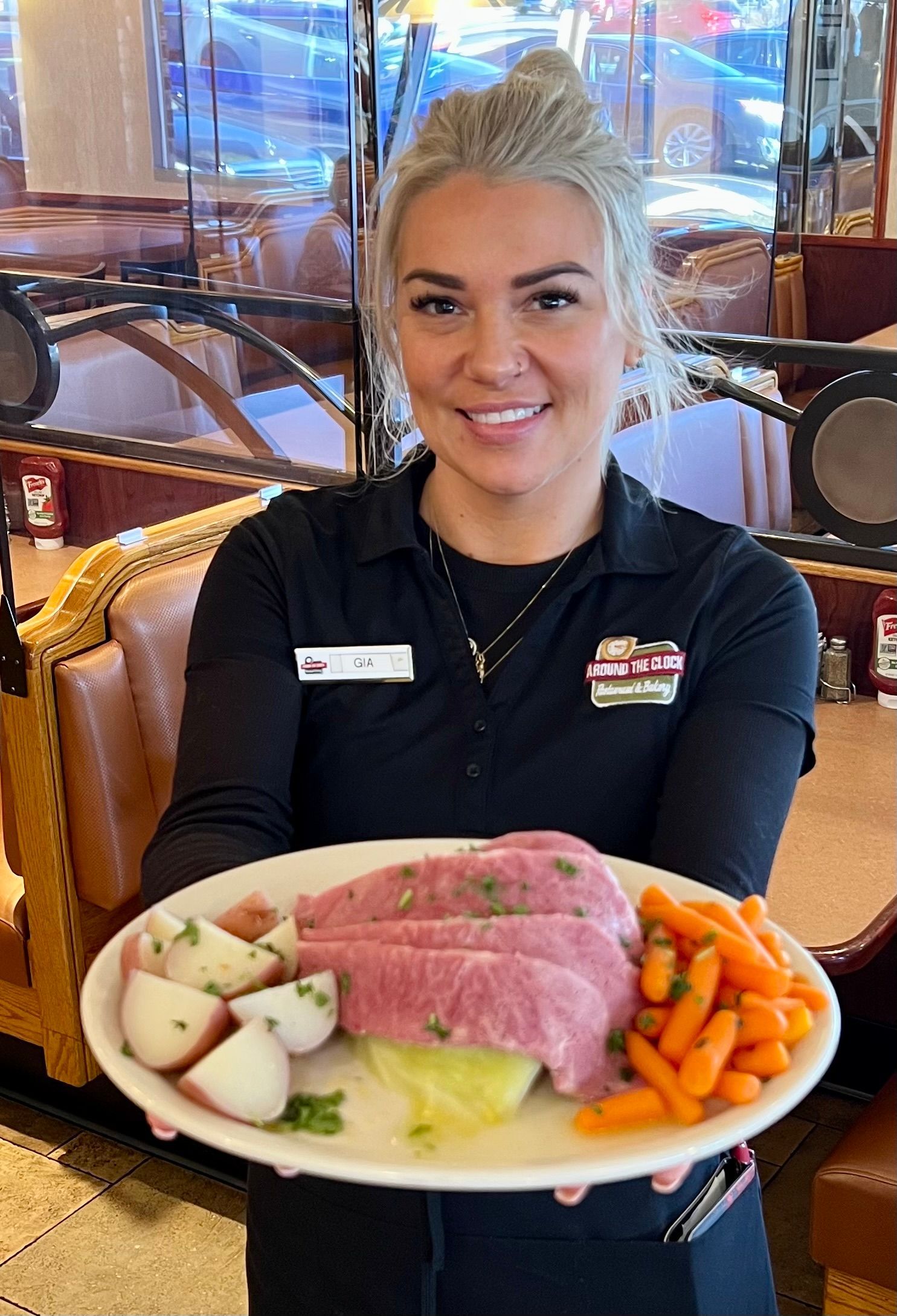 A woman is holding a plate of food in a restaurant.