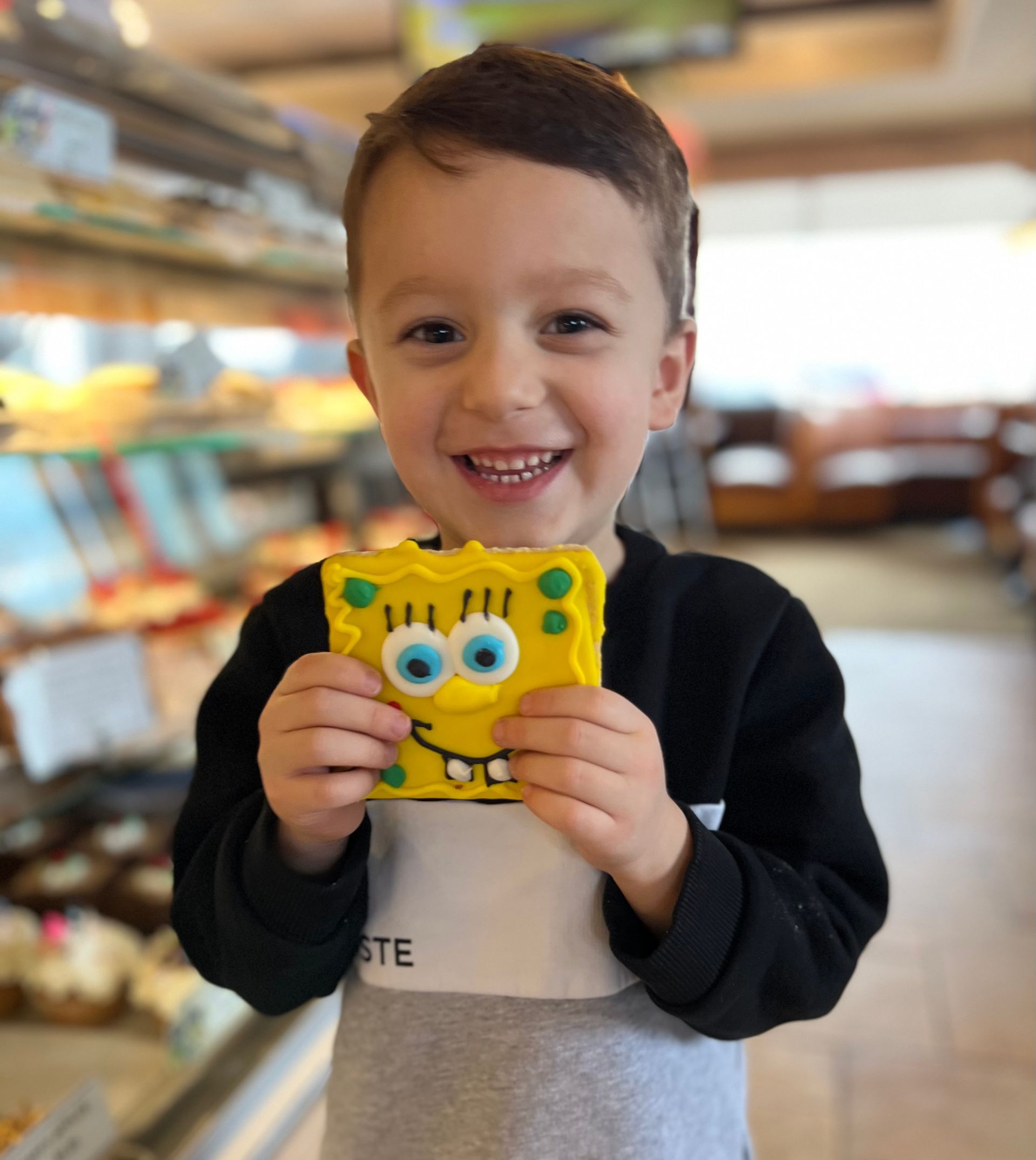 A young boy is holding a spongebob cookie in his hands