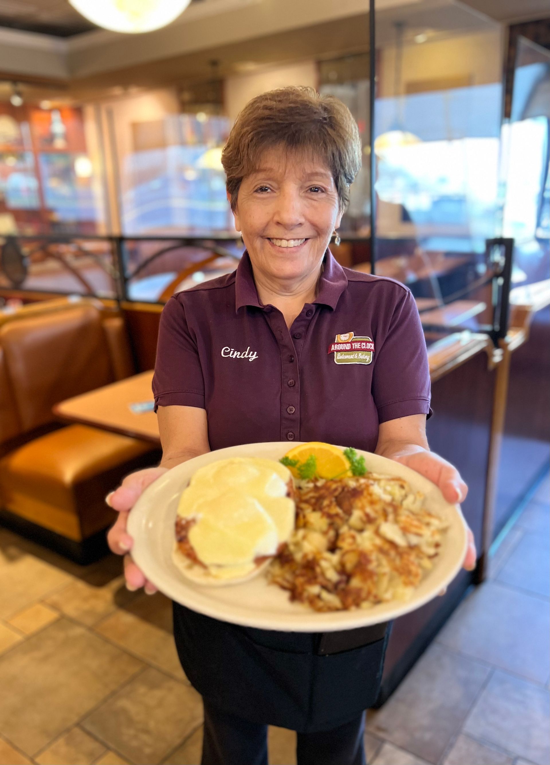 A woman is holding a plate of food in a restaurant.