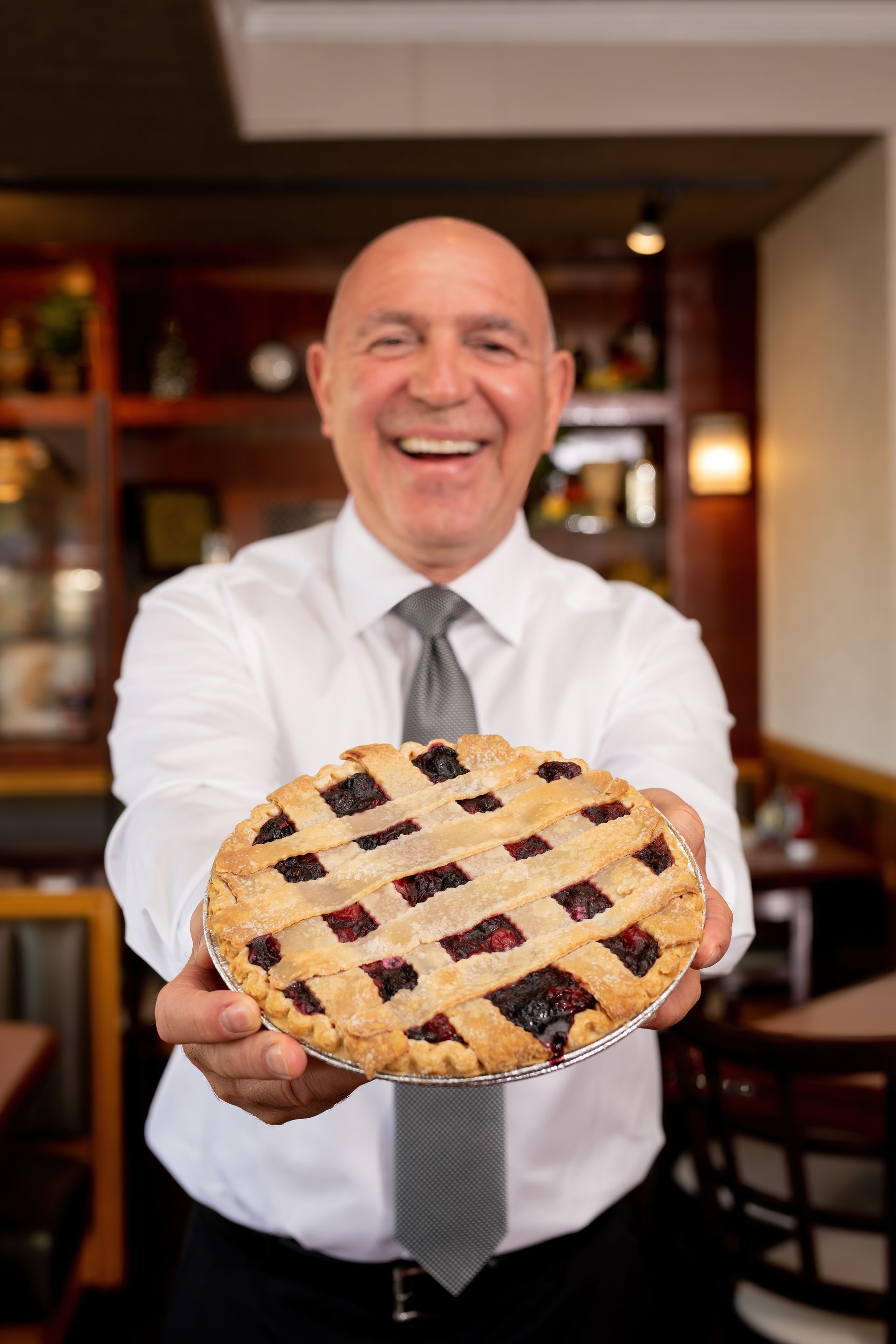 A man in a suit and tie is holding a pie in his hands.