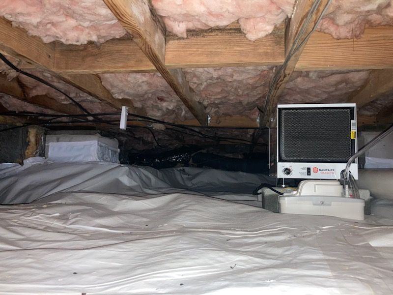 Insulated attic with a portable monitor and white tarp-covered floor。